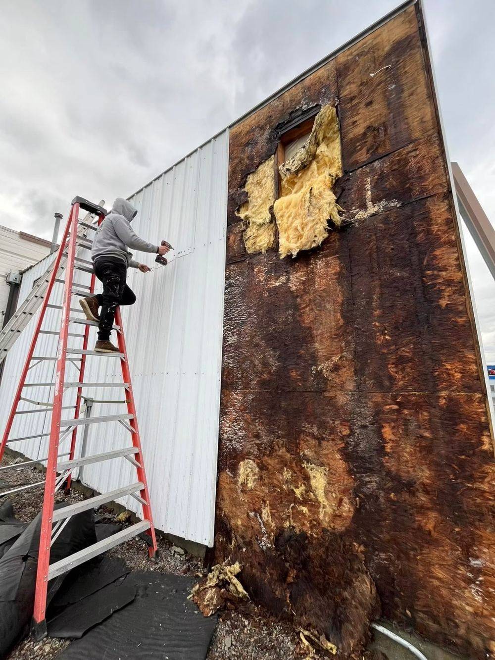 Water-damaged and rotted siding on a building being repaired by Rocky Mountain Home Services